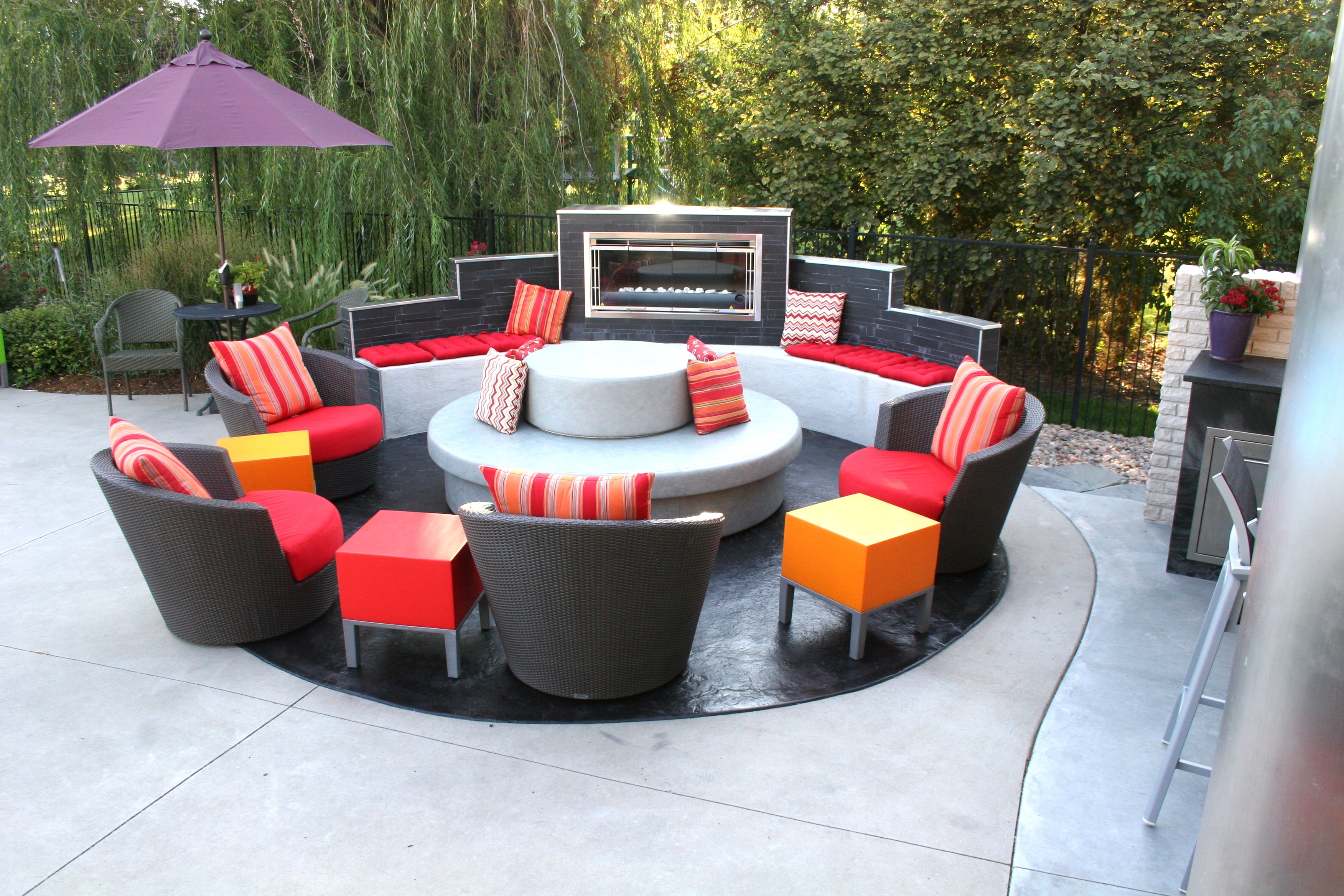 Tri level outdoor fireplace partially surrounding a circular conversation area.